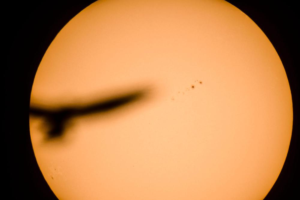 Jobbra az AR 2443 napfolt a Nap felszínén, Cered közeléből fotózva 2015. november 5-én. A csillag felületén látható foltok a mágneses naptevékenység jelei, jól megfigyelhető, körülbelül 11 éves ciklikusságot mutatnak. A periódus csúcspontja közelében megszaporodó napkitörések befolyással lehetnek a Föld mágneses terére, zavarhatják a műholdak és a földi elektromos hálózatok működését. Balra egy viszonylag közeli madár árnya. 
