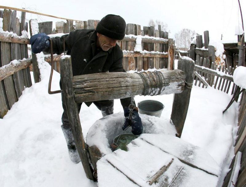 Baburin takes water from well at court yard of his house in remote Siberian village of Mikhailovka